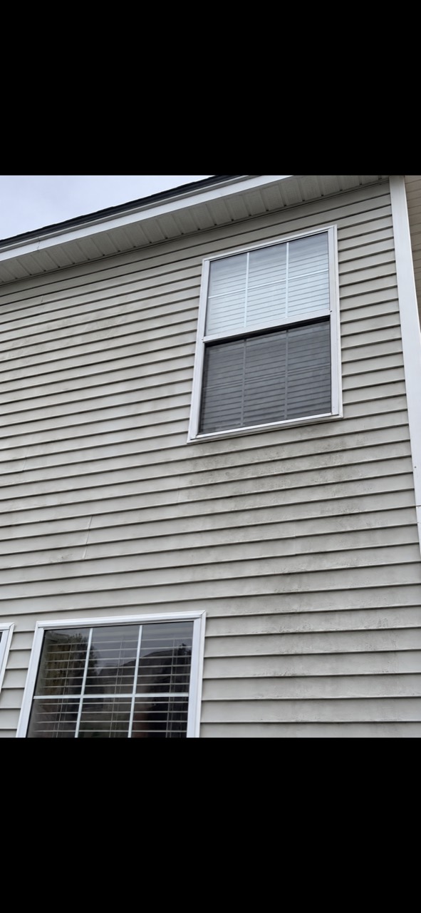 Upper-story siding around a window before house washing